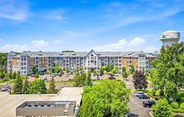 Champlin apartment for rent - A large building with a parking lot in front of it.