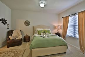 Burleson apartment for rent - a bedroom with a bed and a chair and a clock on the wall at Cedars of Elk Drive 55+ Apartments, Burleson Texas