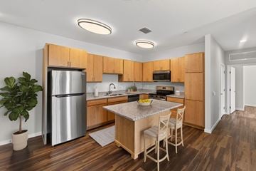 Apopka apartment for rent - A kitchen with wooden cabinets and a stainless steel refrigerator.