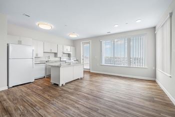 A white kitchen with a large window and a white refrigerator