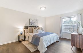 Jonesboro apartment for rent - A bedroom with a bed, nightstand, and a window with a view of a city.