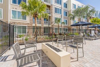 A patio with chairs and a bench in front of a building.