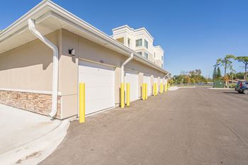 A row of garage doors are yellow and are in front of a building.