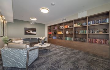 Aurora apartment for rent - A living room with a grey patterned chair and a coffee table in front of a bookshelf.