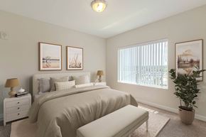 Greenville apartment for rent - A bedroom with a large bed, a nightstand with a lamp, a bench, and three pictures on the wall. at Avery Landing Apartments, Greenville