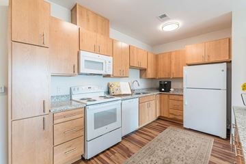 Greenville apartment for rent - A kitchen with wooden cabinets and white appliances.