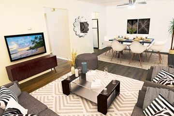 Southfield townhouse for rent - A living room with a grey sofa, a wooden entertainment unit, a coffee table, and a dining table set up.