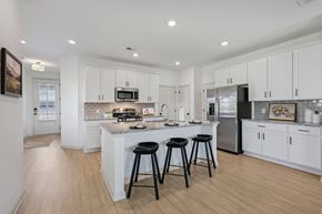Dawsonville townhouse for rent - A kitchen with white cabinets and a white island with three black stools.