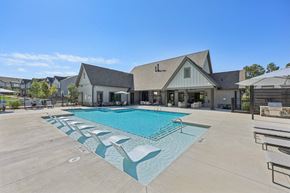 Dawsonville townhouse for rent - A large outdoor swimming pool with lounge chairs and a building in the background.