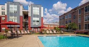 Atlanta apartment for rent - A swimming pool is surrounded by lounge chairs in front of a building.