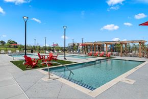 Jarrell apartment for rent - A pool area with red chairs and a wooden pergola.