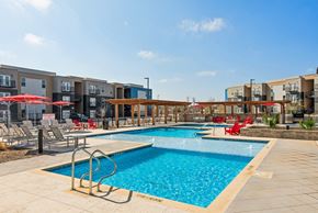 Marble Falls apartment for rent - A swimming pool surrounded by red chairs and umbrellas.