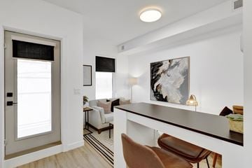 Calgary apartment for rent - A modern living room with a brown leather chair and a white sofa.