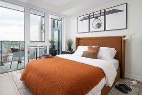 Toronto apartment for rent - A bedroom with a large bed and a view of the city.