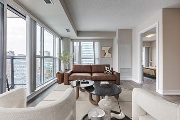 Toronto apartment for rent - A living room with a brown couch and white chairs.