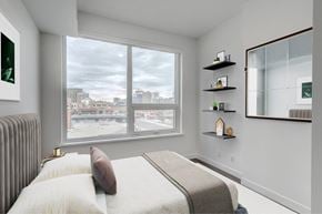 Calgary apartment for rent - A bedroom with a large bed and a view of the city.