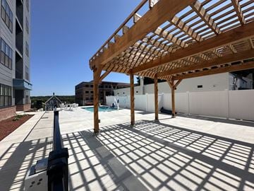 Concord apartment for rent - a covered patio with a pool and a building in the background
