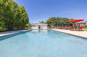 Somersworth apartment for rent - A swimming pool with red umbrellas and a building in the background.