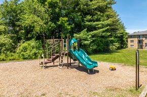 Somersworth apartment for rent - A playground with a green slide and a brown swing set.
