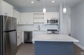 Swanzey apartment for rent - A modern kitchen with a stainless steel refrigerator and white countertops.