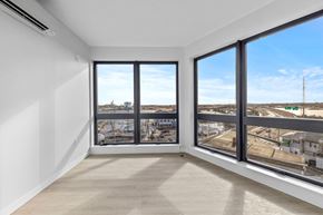 Beverly apartment for rent - A room with a large window overlooking a parking lot and buildings.