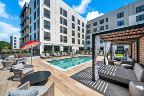 Haverhill apartment for rent - A modern outdoor pool area with a wooden deck and lounge chairs.