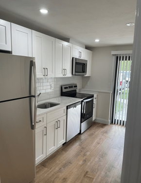 Attleboro apartment for rent - a renovated kitchen with white cabinets and black appliances
