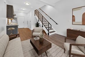 Washington apartment for rent - A living room with a brown sofa, a coffee table, and a staircase.