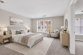 Jessup apartment for rent - A bedroom with a large bed and a chair by the window.
