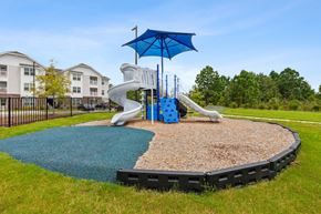 Apex apartment for rent - A playground with a blue umbrella and a slide.