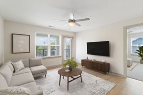 Durham apartment for rent - A living room with a grey couch, a coffee table, a flat screen TV and a ceiling fan.
