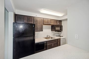 Baltimore apartment for rent - A black refrigerator is in a kitchen with brown cabinets.