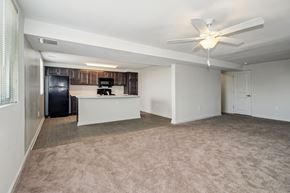 Baltimore apartment for rent - an empty living room with a kitchen and a ceiling fan