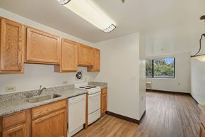 Baltimore apartment for rent - a kitchen with wooden cabinets and white appliances and a window
