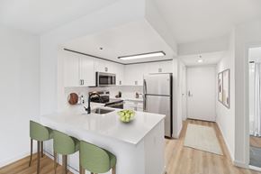 Philadelphia apartment for rent - A kitchen with white cabinets and a white island with green chairs.