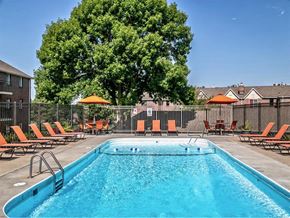 Omaha apartment for rent - a swimming pool with orange chairs and a tree