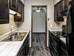 Omaha apartment for rent - a kitchen with black cabinets and a sink and a door to a hallway