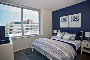 Clayton apartment for rent - A bedroom with a large bed and a view of the city at Two Twelve Clayton Apartments, Clayton, MO, 63105