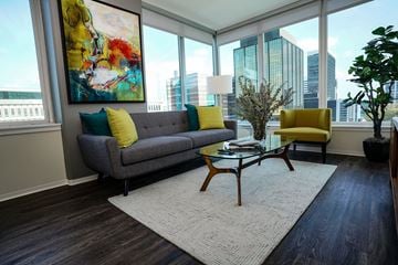 Clayton apartment for rent - A living room with a grey couch and yellow pillows.
