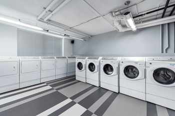A row of white front load washing machines in a laundromat.
