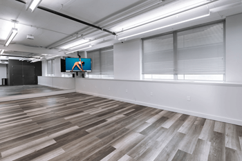 A spacious room with wooden flooring and a large screen displaying an orange figure.