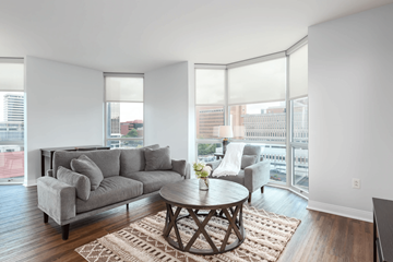 Clayton apartment for rent - A living room with a grey couch, a coffee table and a large window.