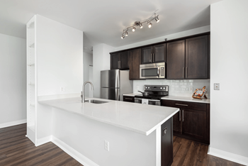 A kitchen with white countertops and dark brown cabinets.