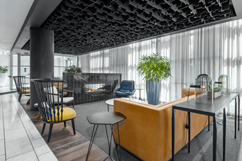 A modern office space with a wooden reception desk and black chairs.