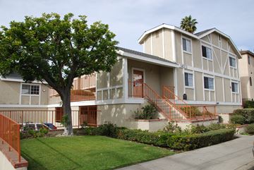 Hawthorne apartment for rent - A tree in front of a two-story building with a red railing.
