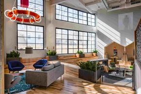 Cleveland apartment for rent - A modern office space with a large window, a blue chair, and a wooden floor.