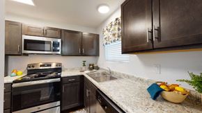 Evansville townhouse for rent - A kitchen with dark brown cabinets and granite countertops.