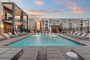 Albuquerque apartment for rent - A swimming pool surrounded by lounge chairs and buildings.