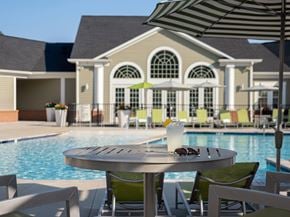 Windsor Mill apartment for rent - A table with a glass of milkshake and sunglasses on it in front of a pool.