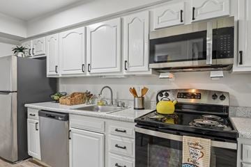 White Marsh townhouse for rent - A kitchen with white cabinets and a black stove top.